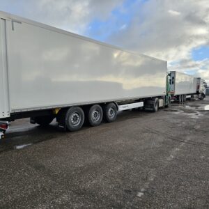 Sunkvežimio puspriekabė stovi aikštelėje dienos metu debesuota, nufotografuota iš galo